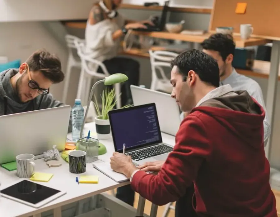 Software developers seated around table with laptops collaborating on project